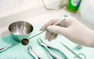 Dentist holding a mirror tool above stainless steel instruments