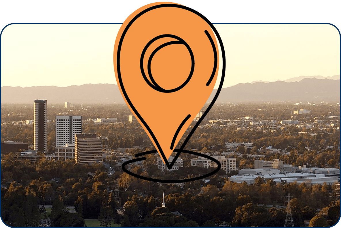 Large location pin icon over an aerial view of Burbank CA skyline with tall buildings, trees, and mountains at sunset
