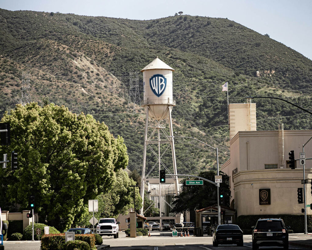 Iconic Warner Bros. water tower in Burbank CA near Olive Avenue, framed by trees and studio buildings