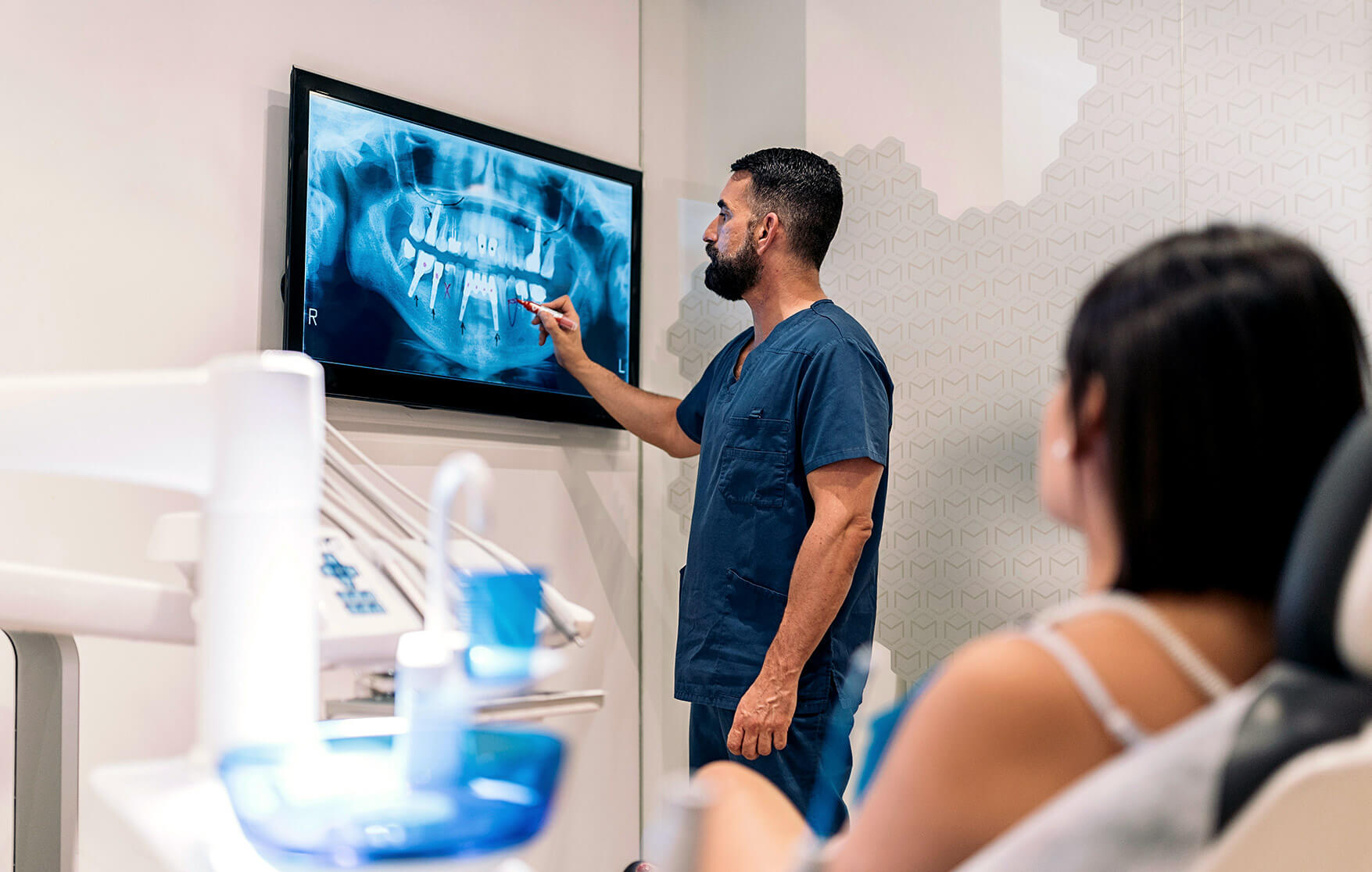 Dentist explains dental X-ray to patient on wall monitor