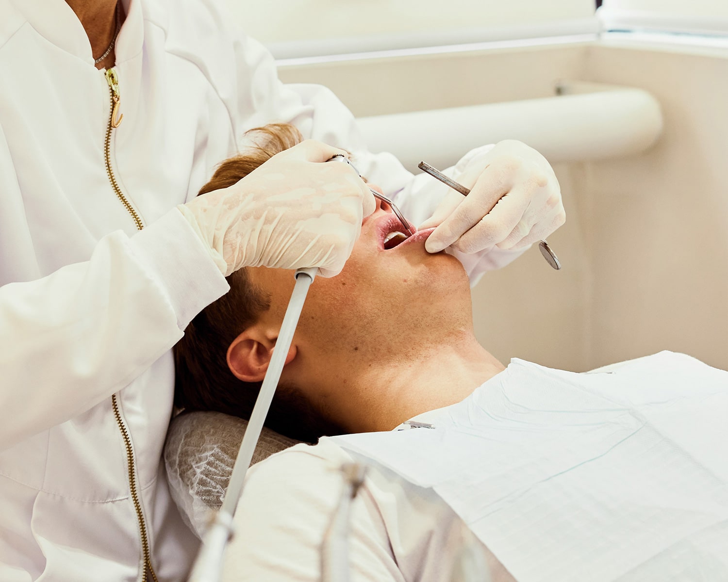 Dentist examining young patient’s mouth with dental tools during checkup