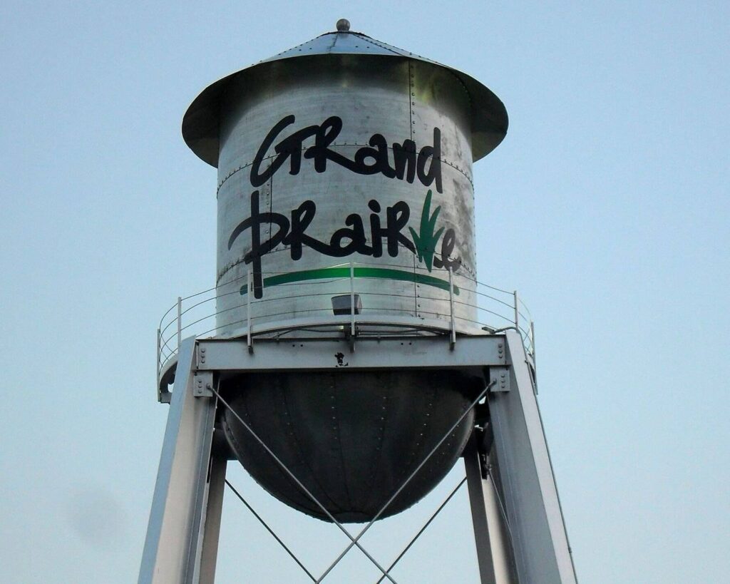 Iconic Grand Prairie, TX water tower with city name logo against a clear blue sky