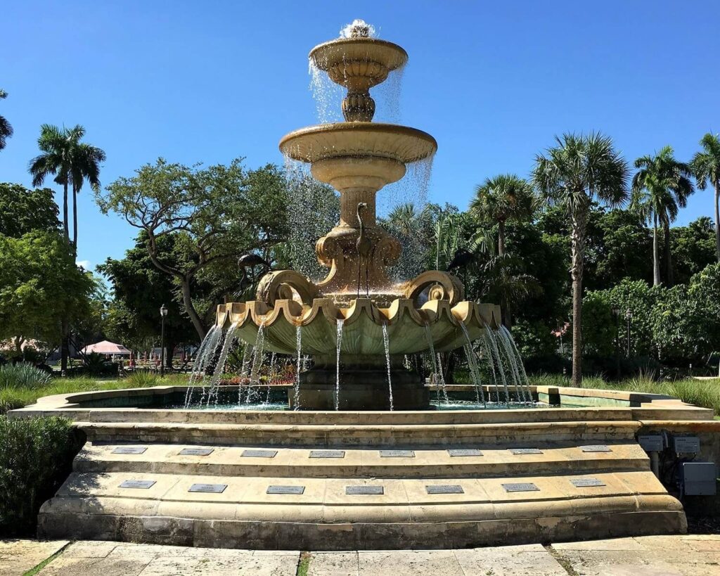 Historic fountain at Hialeah Park in Hialeah, Florida surrounded by palm trees and greenery