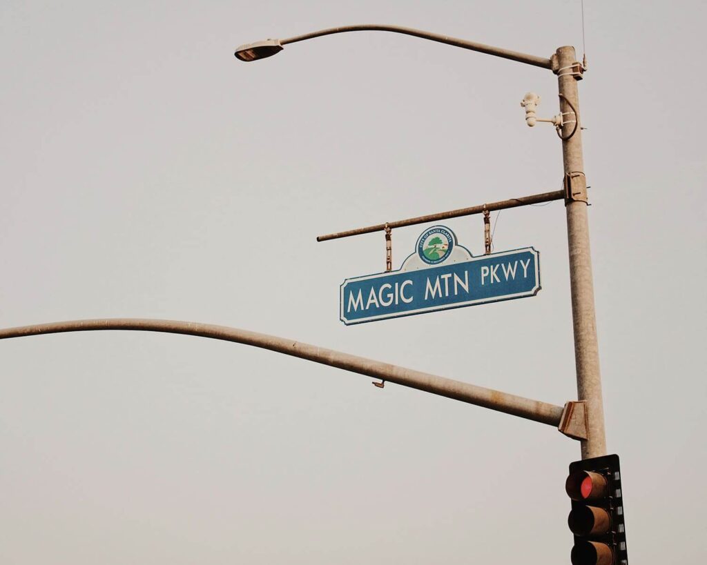Magic Mountain Parkway street sign in Santa Clarita CA hanging from traffic light pole against sky