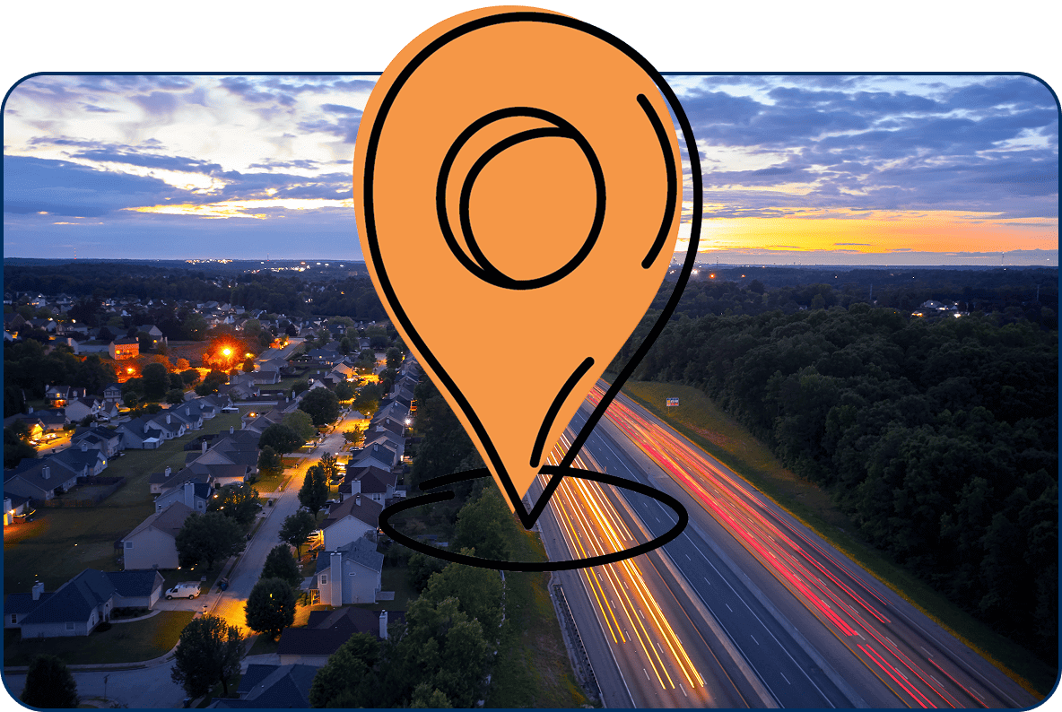 Large location pin icon on aerial view of Stockbridge, Georgia at dusk with neighborhood lights and highway traffic trails