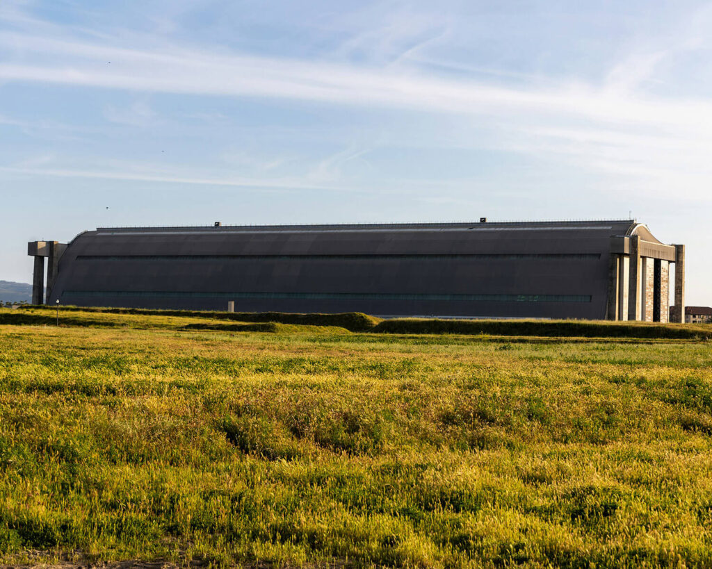 Historic blimp hangar in Tustin, California, surrounded by open grass fields under a blue sky