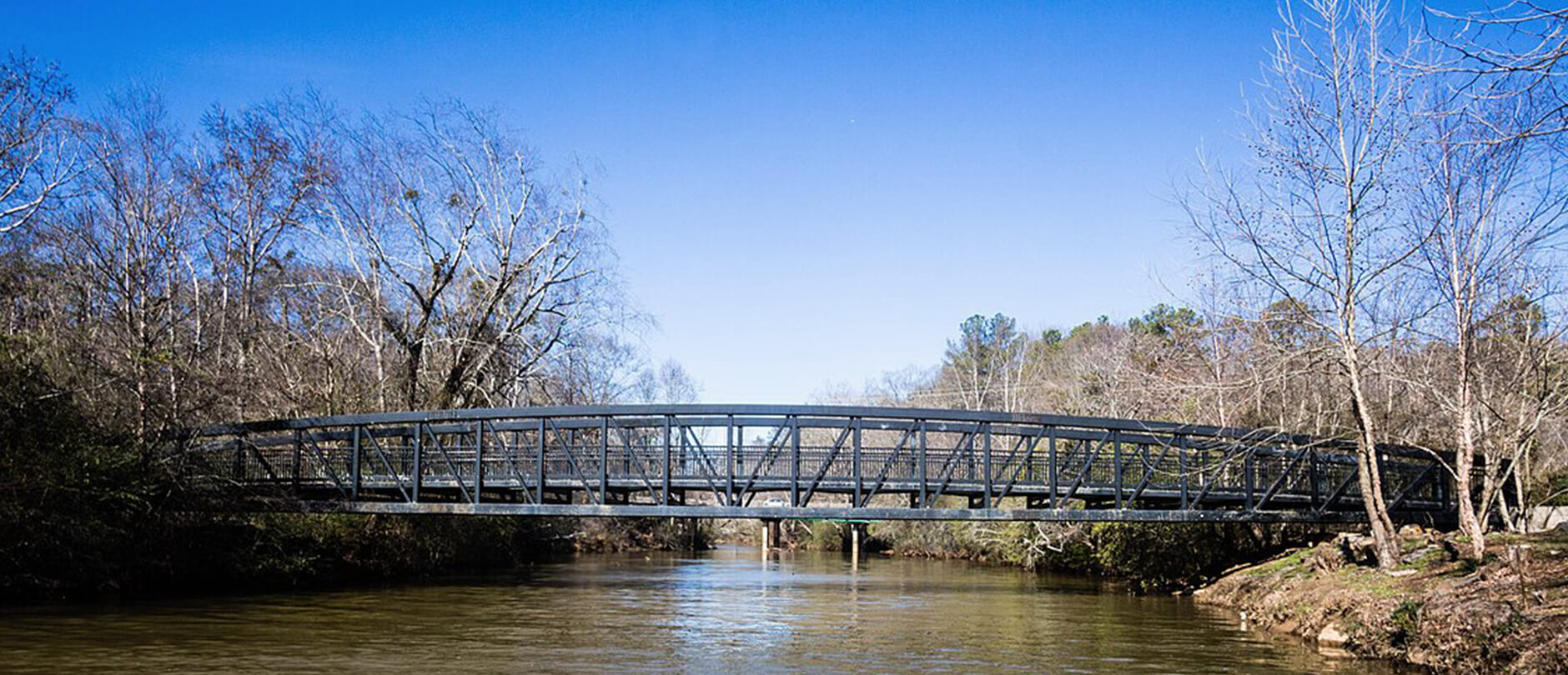 Vickery Creek Bridge over the Chattahoochee River surrounded by trees under a clear blue sky