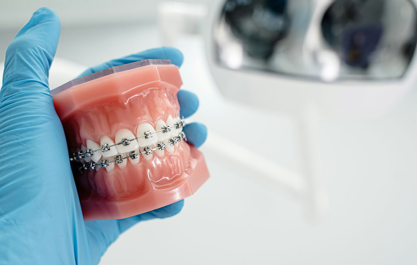 Orthodontist adjusting metal braces during an emergency dental appointment