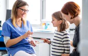 Pediatric dentist explaining dental care to a child with a parent present