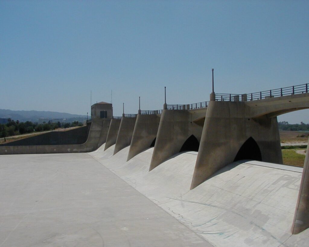 Sepulveda Dam Los Angeles with concrete spillway structure and water control gates under clear sky