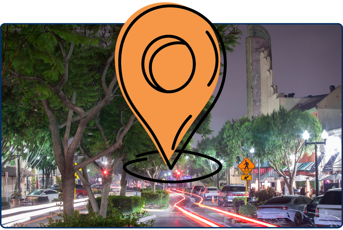 Night street view of historic downtown Inglewood California with trees, traffic light trails, and urban buildings