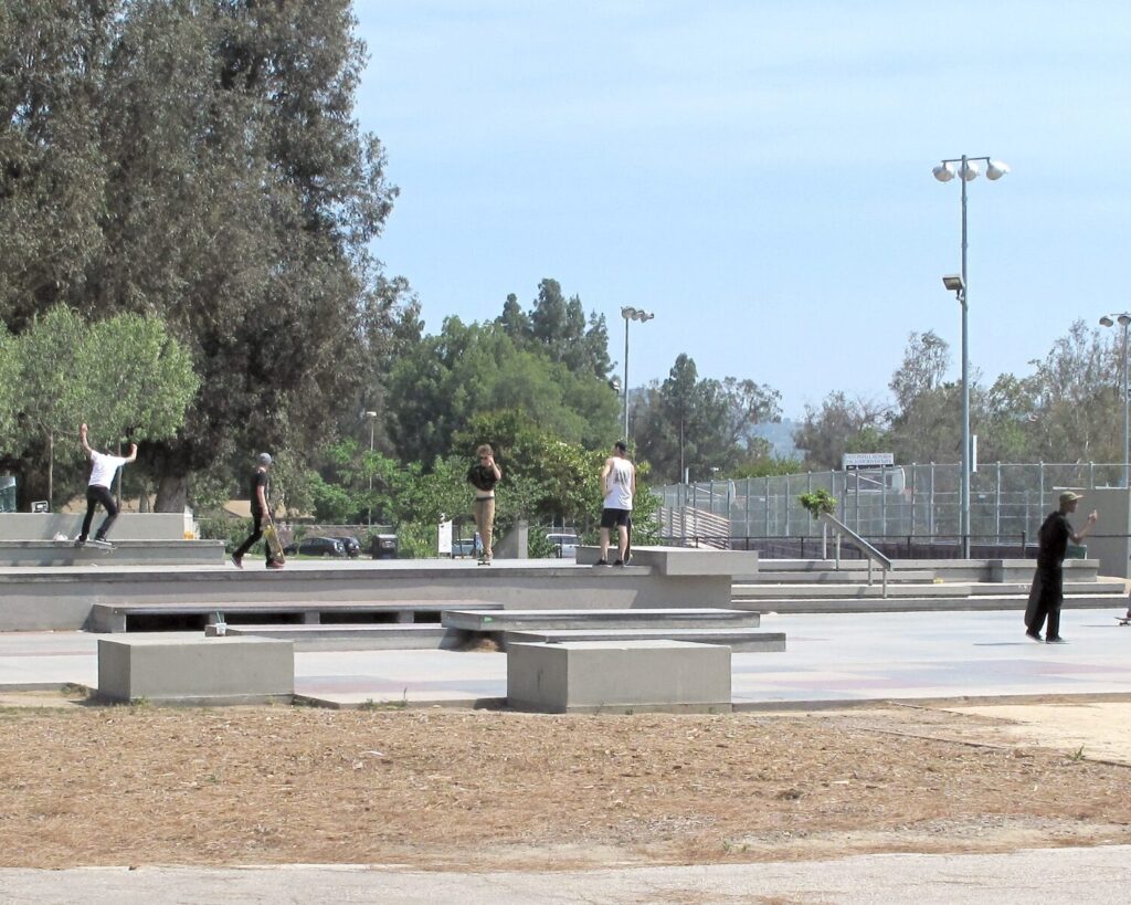 North Hollywood LA Metro station entrance with palm trees, pedestrians, and transit signage in urban setting