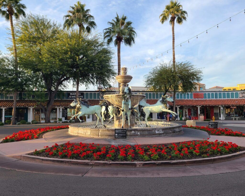 Bronze horse fountain in Scottsdale Arizona surrounded by palm trees, flowers and Old Town shops