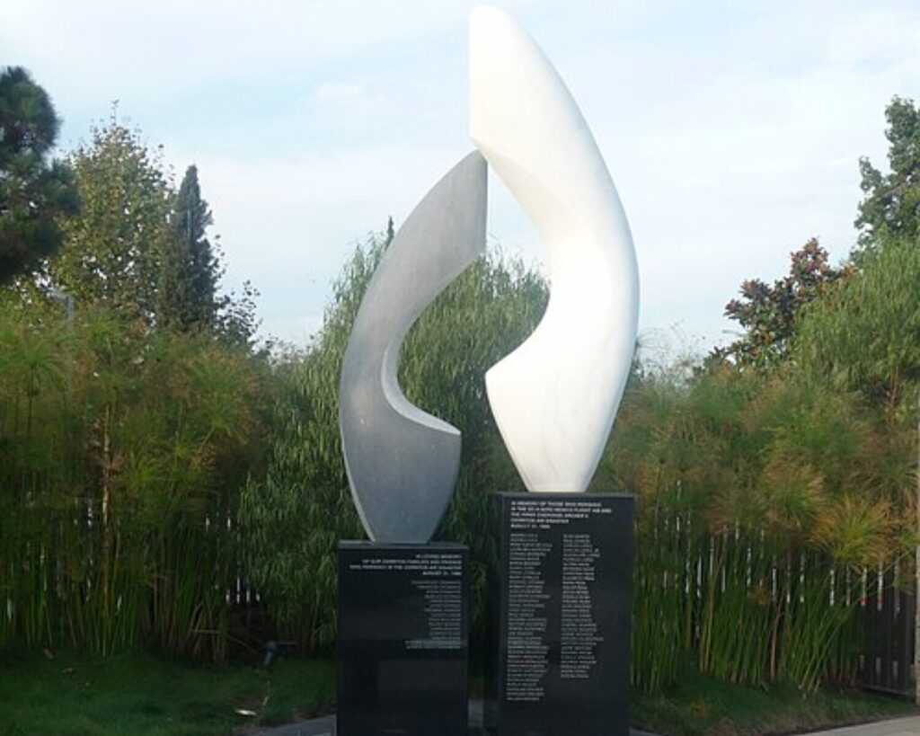 Abstract white and gray sculpture at Cerritos Air Disaster Memorial, with engraved black plaques and surrounding greenery