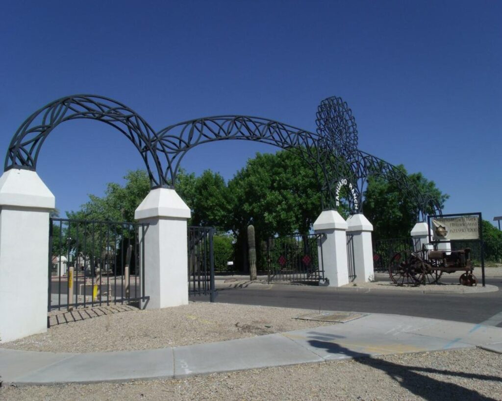 Entrance arch at Sahuaro Ranch Park in Glendale Arizona with wrought iron structure, desert landscaping and historic park gate