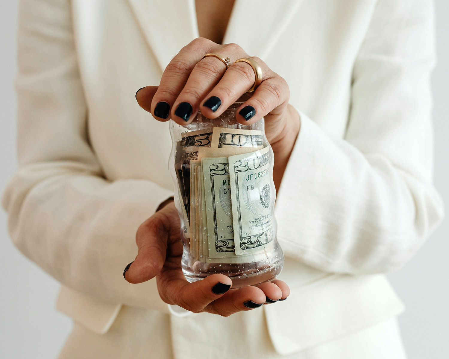 Person holding jar filled with cash symbolizing savings or flexible dental payment options