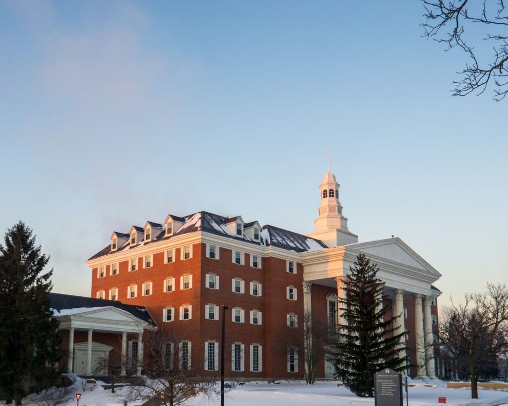 Historic university building with red brick architecture white columns winter snow landscape clear sky academic campus setting