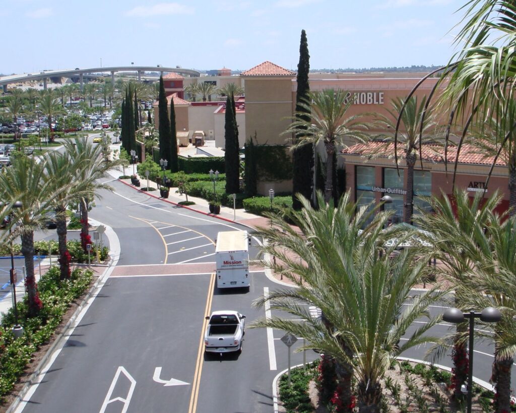 Irvine Spectrum shopping center in California with palm trees road cars and retail stores during daytime view