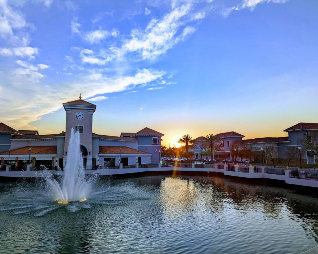 Kendall Miami Florida waterfront plaza with fountain clock tower buildings sunset sky and reflections in water