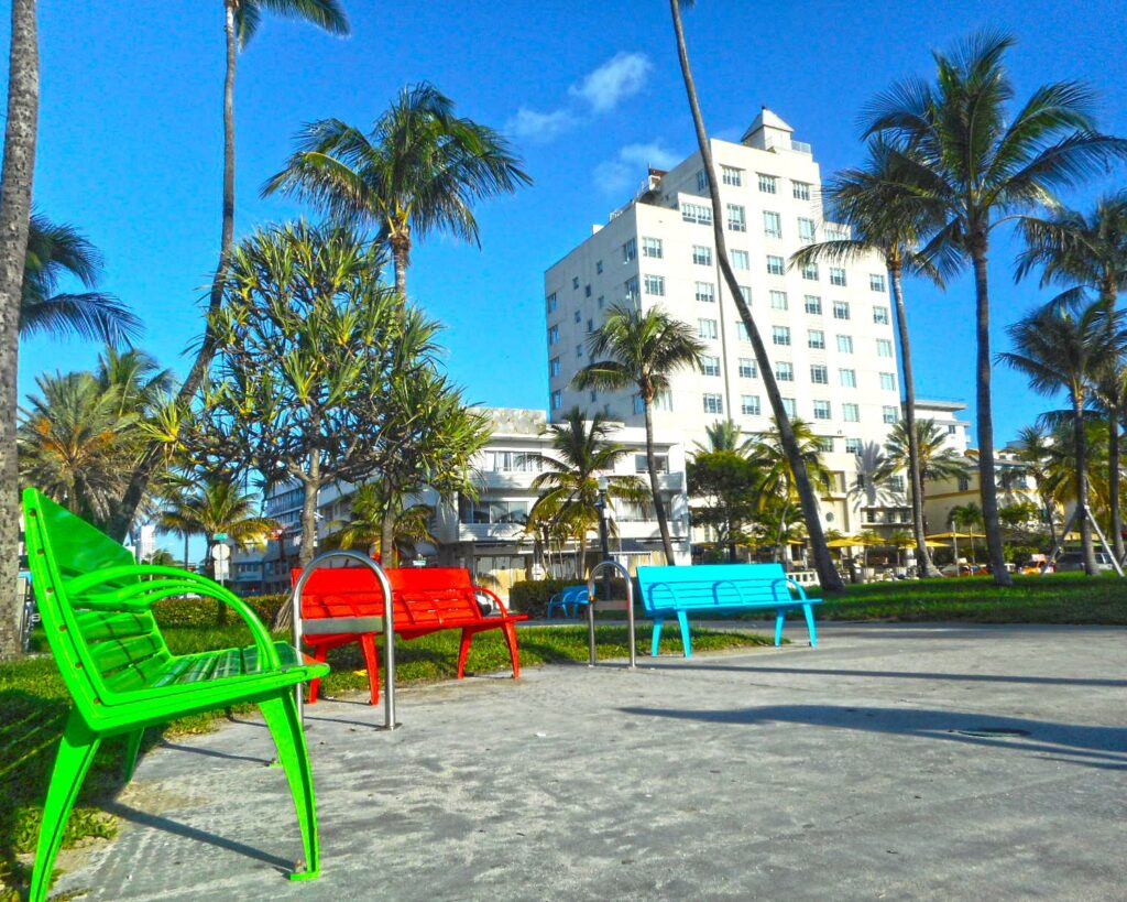 South Beach Miami buildings near Lummus Park with colorful benches palm trees and clear blue sky in Florida