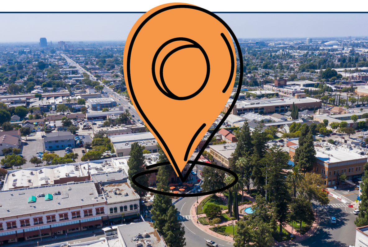 Aerial view of historic Orange, California, showing a dense urban neighborhood with low-rise buildings, tree-lined streets, and a central circular plaza surrounded by roads.