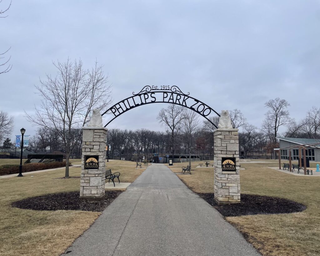 Entrance to Phillips Park Zoo Aurora Illinois with stone arch gate pathway trees and park surroundings