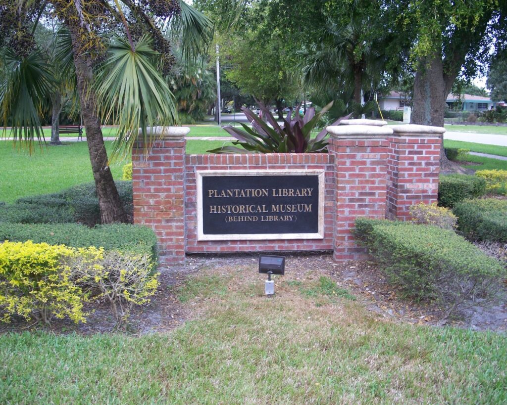 Plantation Florida Historical Museum sign with brick structure greenery trees and landscaped garden area