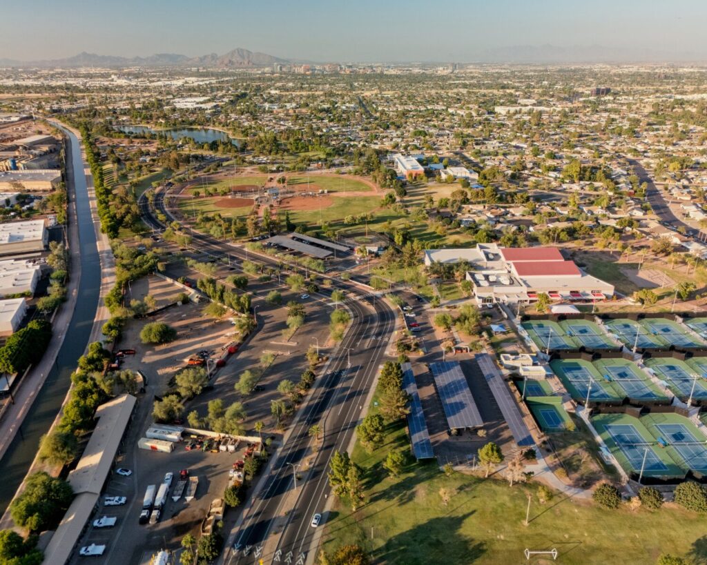 Aerial view of Kiwanis Park in Tempe, Arizona featuring baseball fields, tennis courts, a canal, and surrounding residential neighborhoods with mountains in the distance