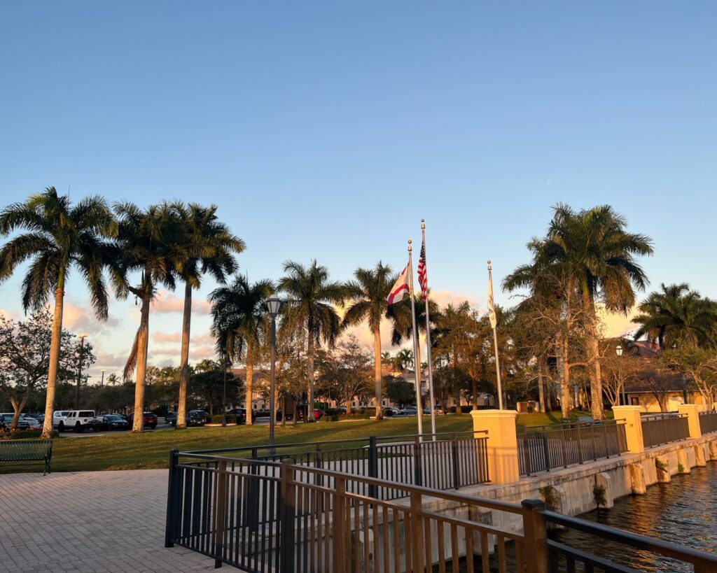 Town Center Park Weston Florida with palm trees waterfront walkway flags and evening sunlight sky