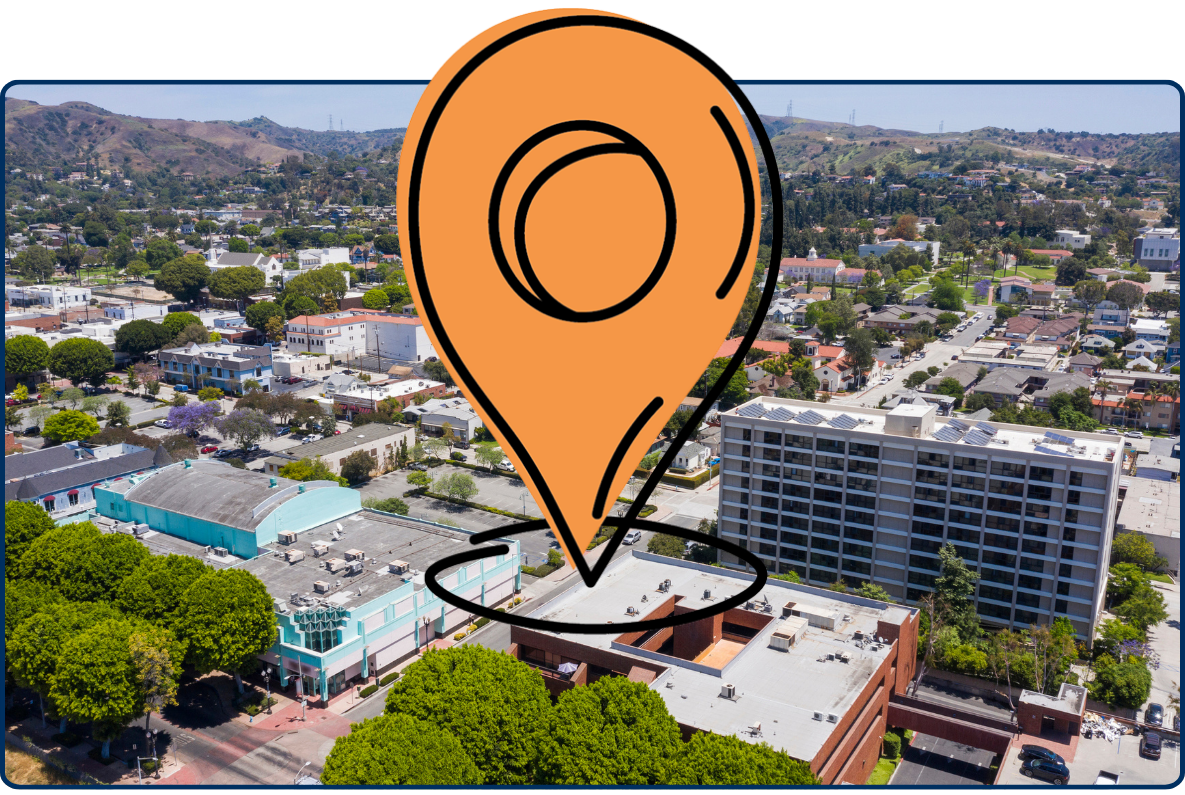 Aerial view of Whittier California with residential buildings streets trees and hills in background under clear sky