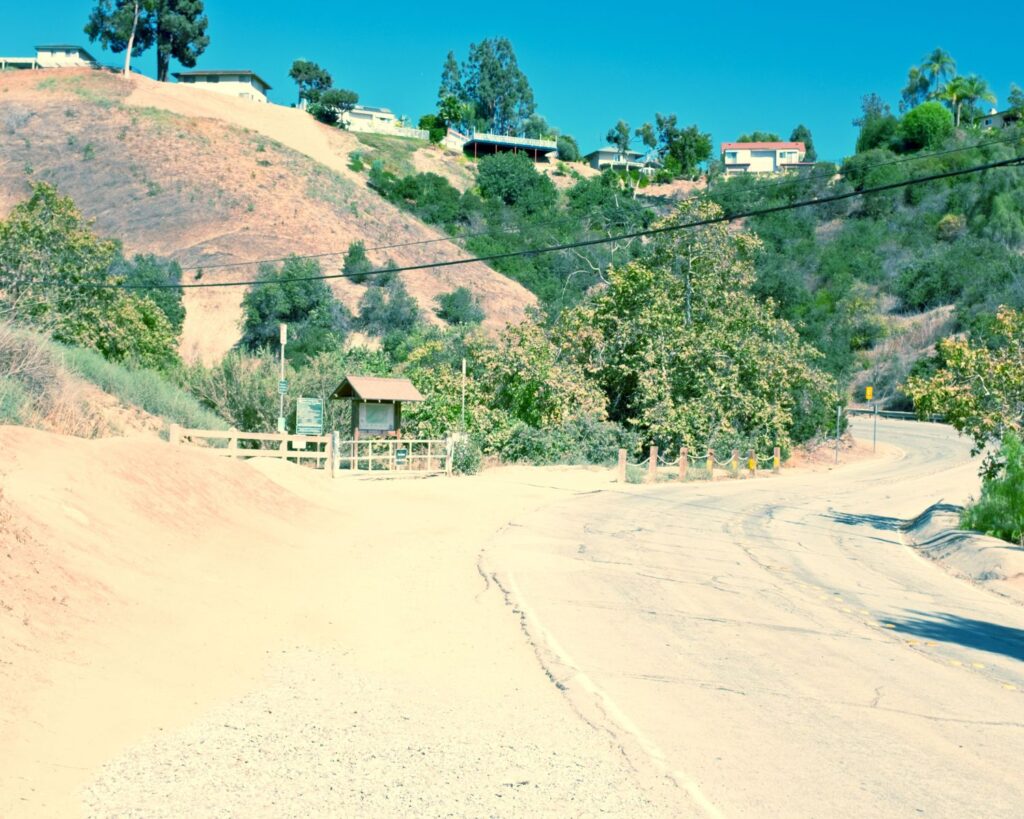 Entrance to Turnbull Canyon Trail in Hellman Wilderness Park Whittier California with dirt path hills and clear blue sky
