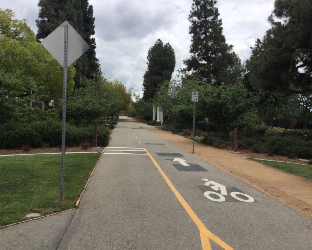 Whittier Greenway Trail in Palm Park with cycling path trees greenery and cloudy sky in California