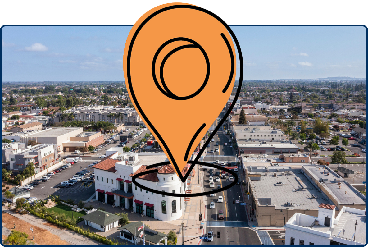 Aerial view of Bellflower, California showing a busy main street lined with buildings, homes, and parked cars.