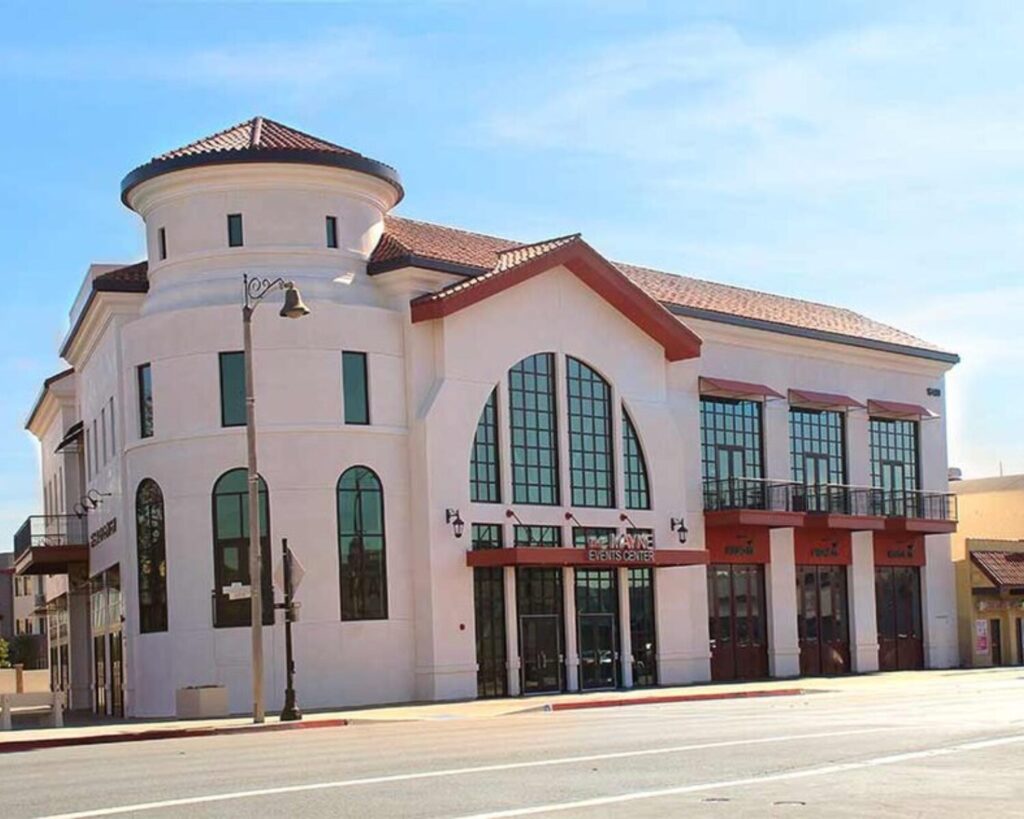 The Mayne Events Center in Bellflower, California, featuring a white stucco facade with arched windows and a round tower.