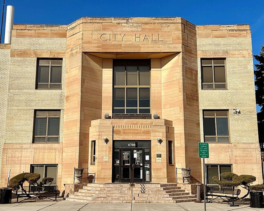 Front view of Berwyn City Hall, a symmetrical brick building with central entrance, steps, and “City Hall” inscription above the doorway.