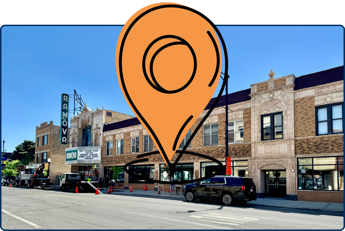 Street view of the historic Ramova Theatre in the Bridgeport neighborhood of Chicago, Illinois, featuring a long brick facade with decorative architectural details, a vintage vertical theater sign, parked vehicles, and a wide city street under a clear blue sky.