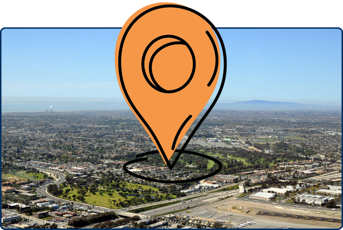 Aerial view of Costa Mesa with urban neighborhoods, highways, green spaces, and coastline in the distance under a clear sky.