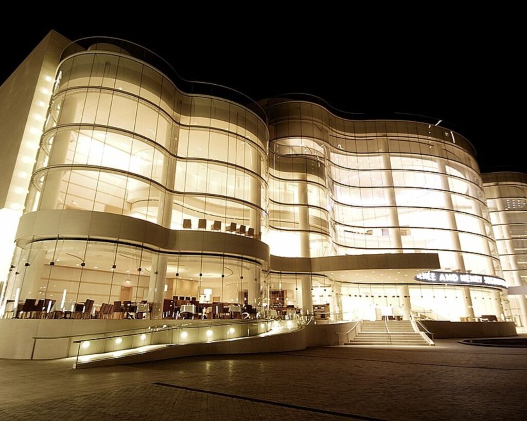 OC Performing Arts Center building illuminated at night with modern glass architecture and curved design.