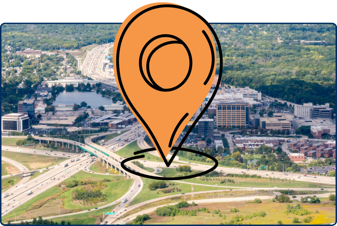 Aerial view of the I-90 and I-294 interchange in Des Plaines, Illinois, with highways, office buildings, and surrounding green forest areas.