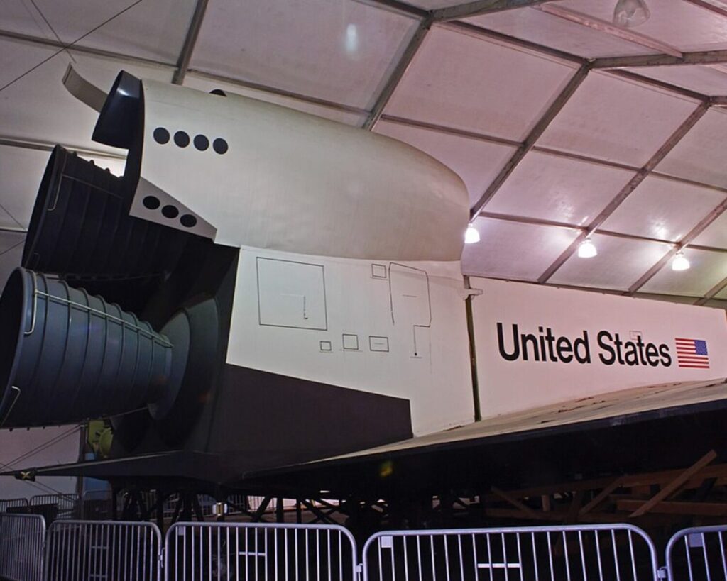 Space shuttle Inspiration tail section with engines and “United States” marking displayed indoors.