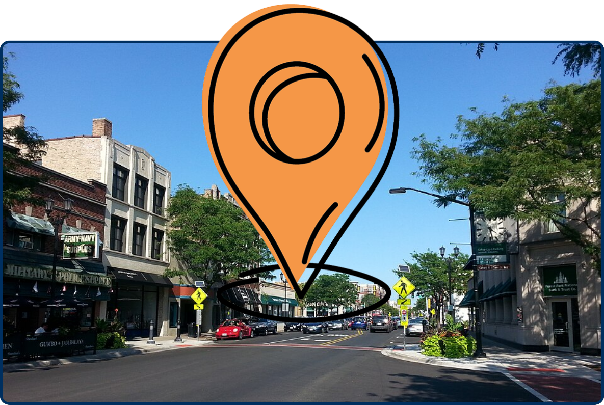 Madison Street in Forest Park, Illinois, lined with local shops, parked cars, trees, and pedestrian crossings on a sunny day.