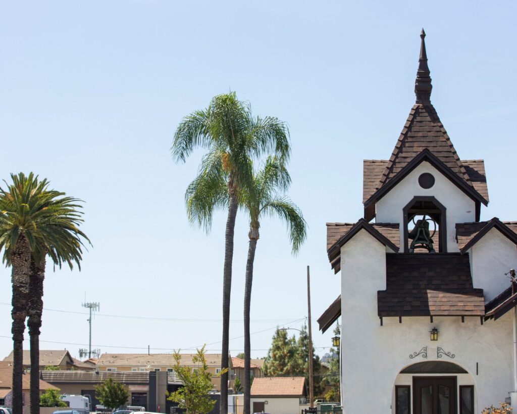 Church-style building with a bell tower and palm trees in La Habra, California under a clear blue sky.