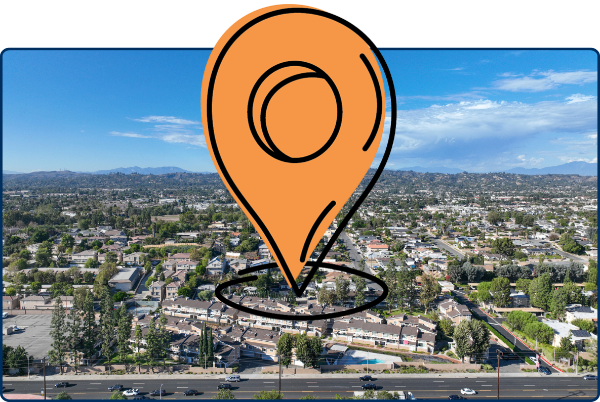 Aerial view of La Habra city with residential neighborhoods, roads, and distant hills under a clear blue sky.