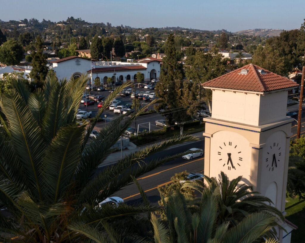 Elevated view of La Habra, California with palm trees, residential buildings, roads, and a clock tower in the foreground.