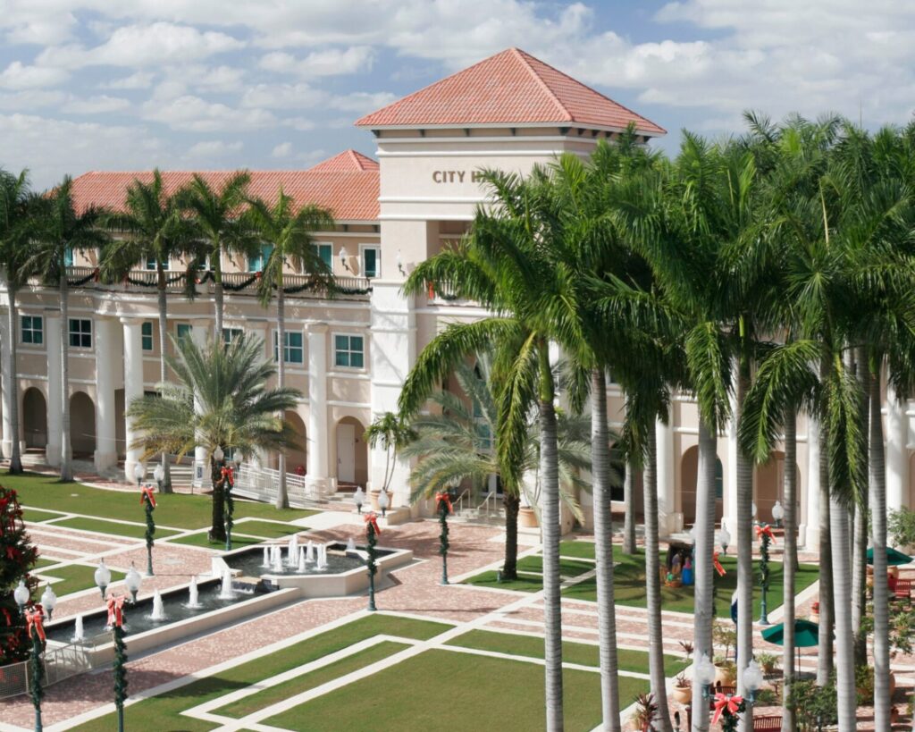 Miramar City Hall building with palm trees, courtyard, and fountain on a sunny day.