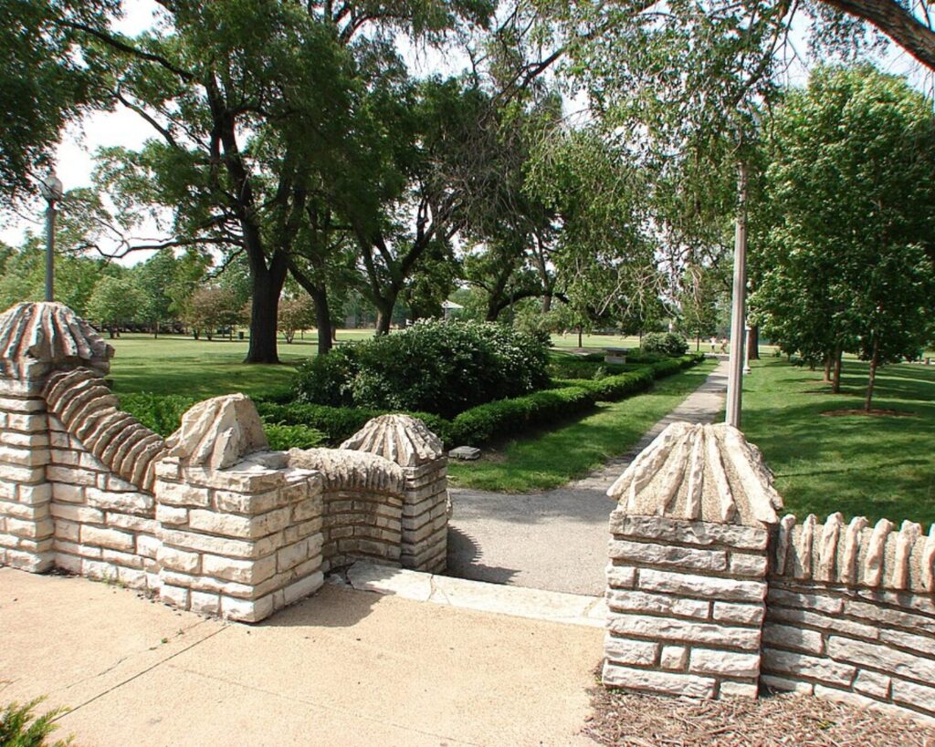Decorative stone entrance steps and landscaped walkway in Portage Park, Chicago, surrounded by trees, lawns, and garden hedges.