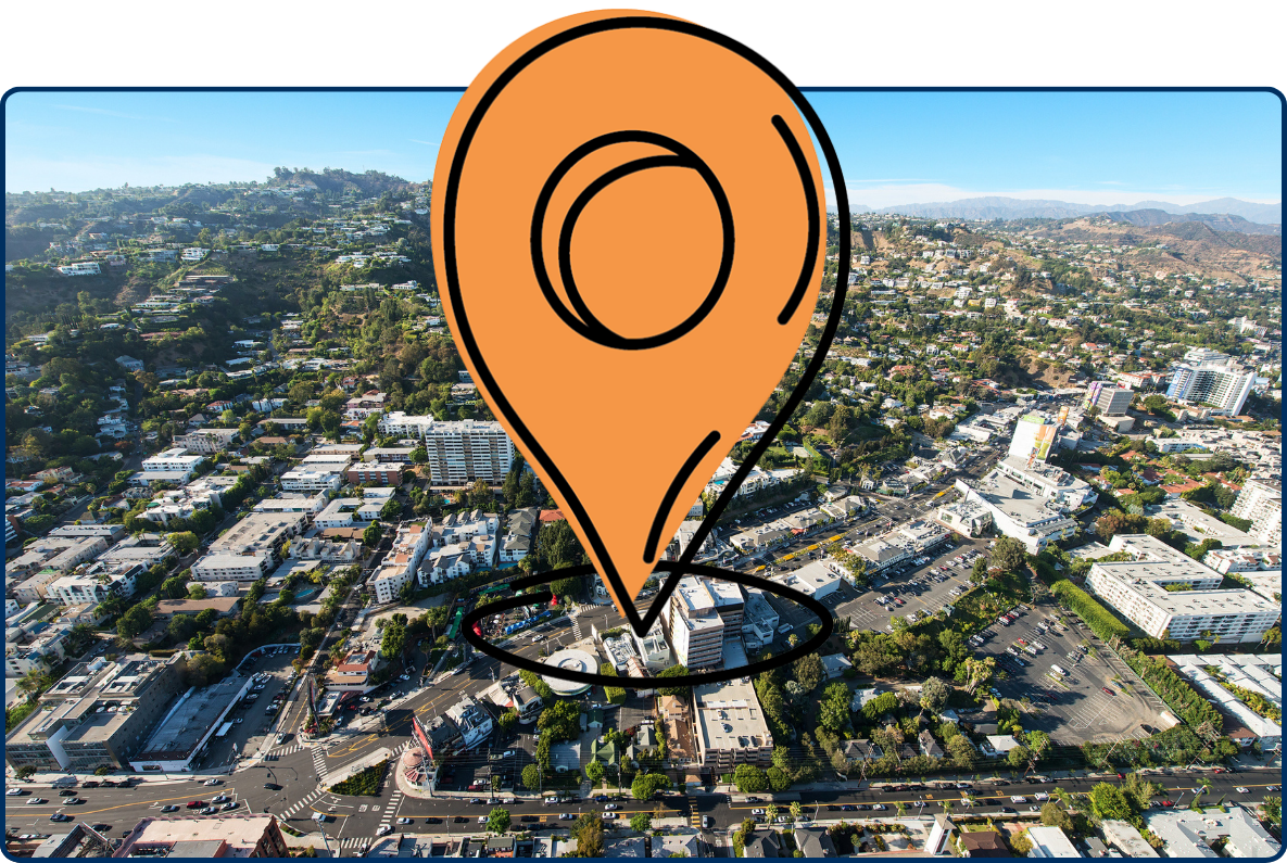 Aerial view of West Hollywood, California, showing Sunset Boulevard, hillside homes, urban buildings, and surrounding mountains under a clear blue sky.