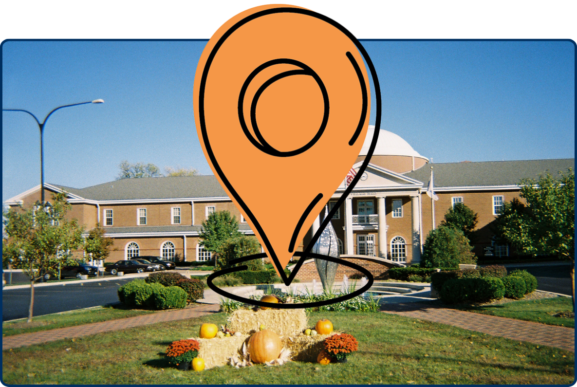 Addison Village Hall exterior with dome, fountain, lawn, and fall decorations under a clear blue sky.
