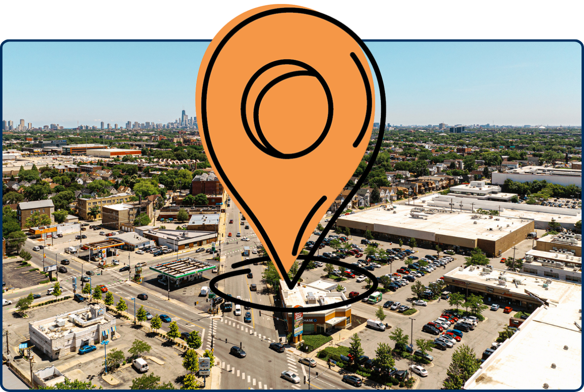 Aerial view of Chicago skyline from Avondale with a long city road, low-rise buildings, parking lots, and clear blue sky.