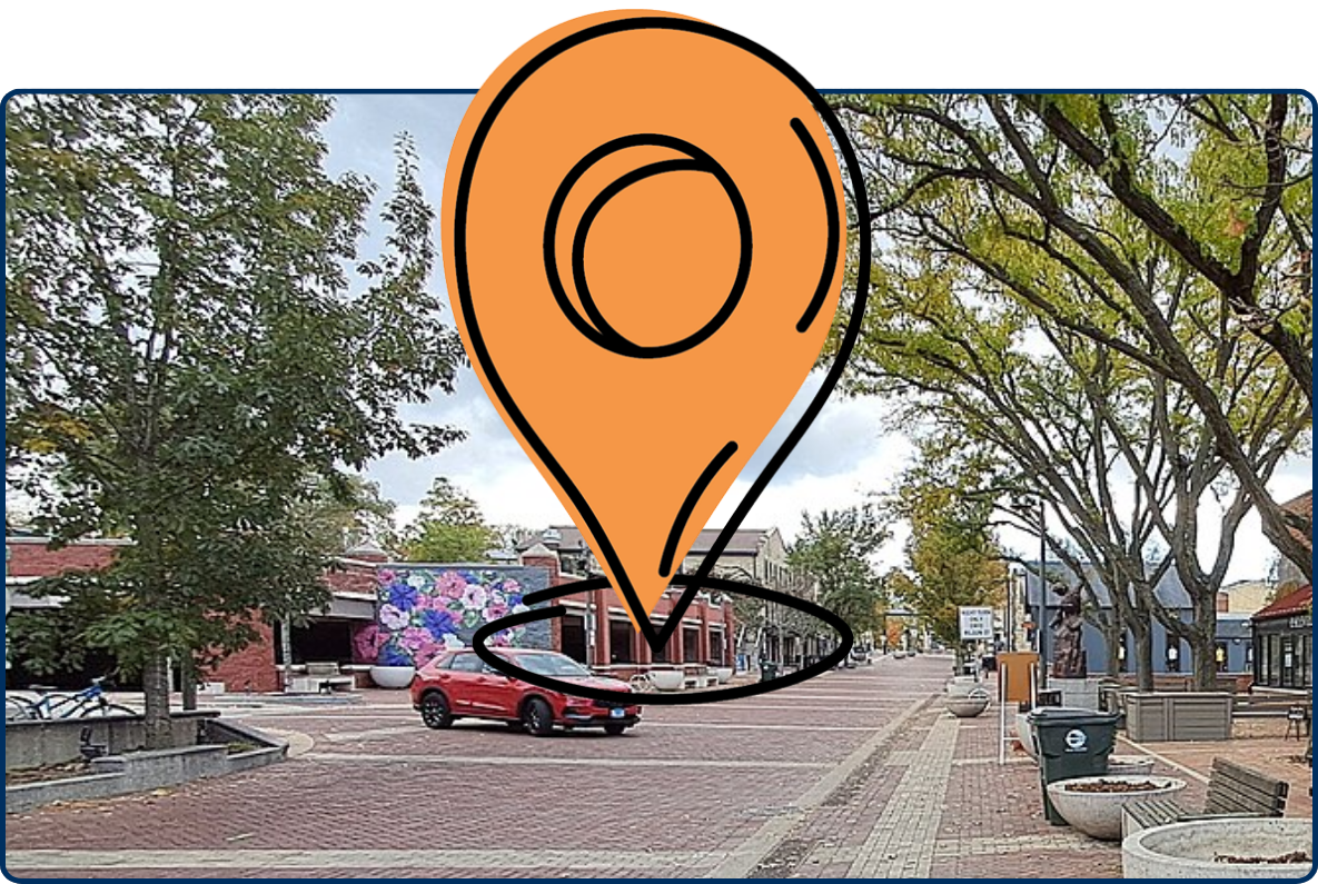 Shared street in Batavia, Illinois with brick road, sidewalk seating, storefronts, trees, and road-sharing signs.
